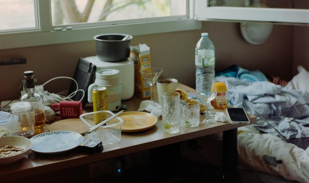 An overwhelmed individual surrounded by clutter, symbolizing mental overwhelm.