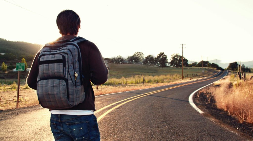 A solitary traveler removing a backpack at sunrise, symbolizing the emotional release of burdens not theirs to carry.